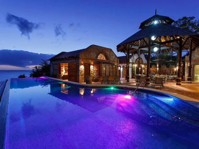 Night view of a villa, gazebo, and illuminated pool